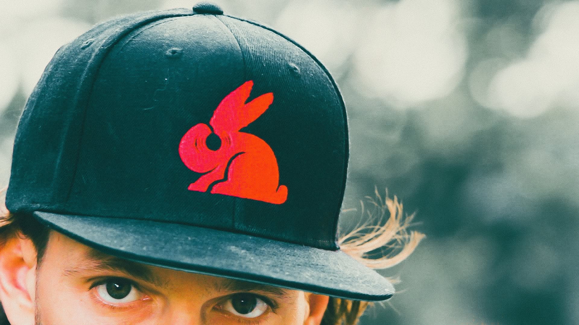 Close-up of a guest in a black snapback with the red Red Rabbit logo