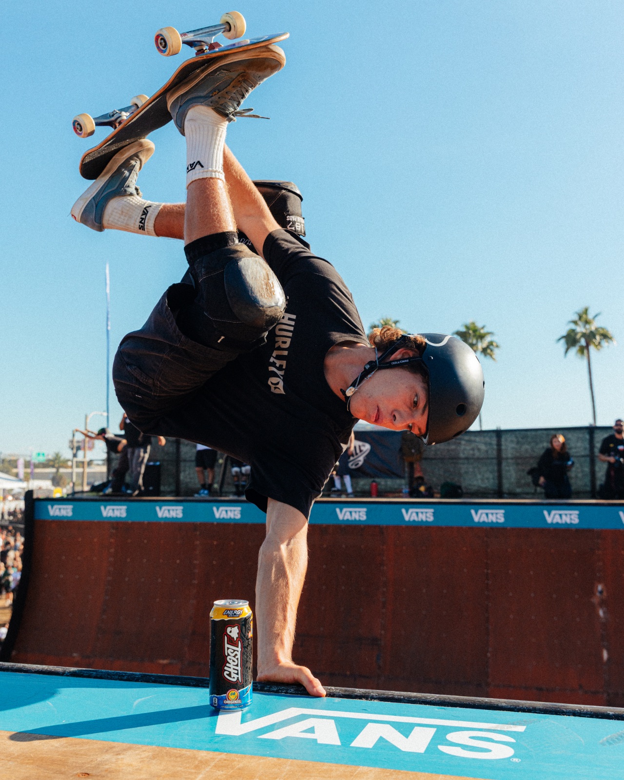 Skater holding a one-handed invert over the Vans ramp coping, GHOST can in foreground