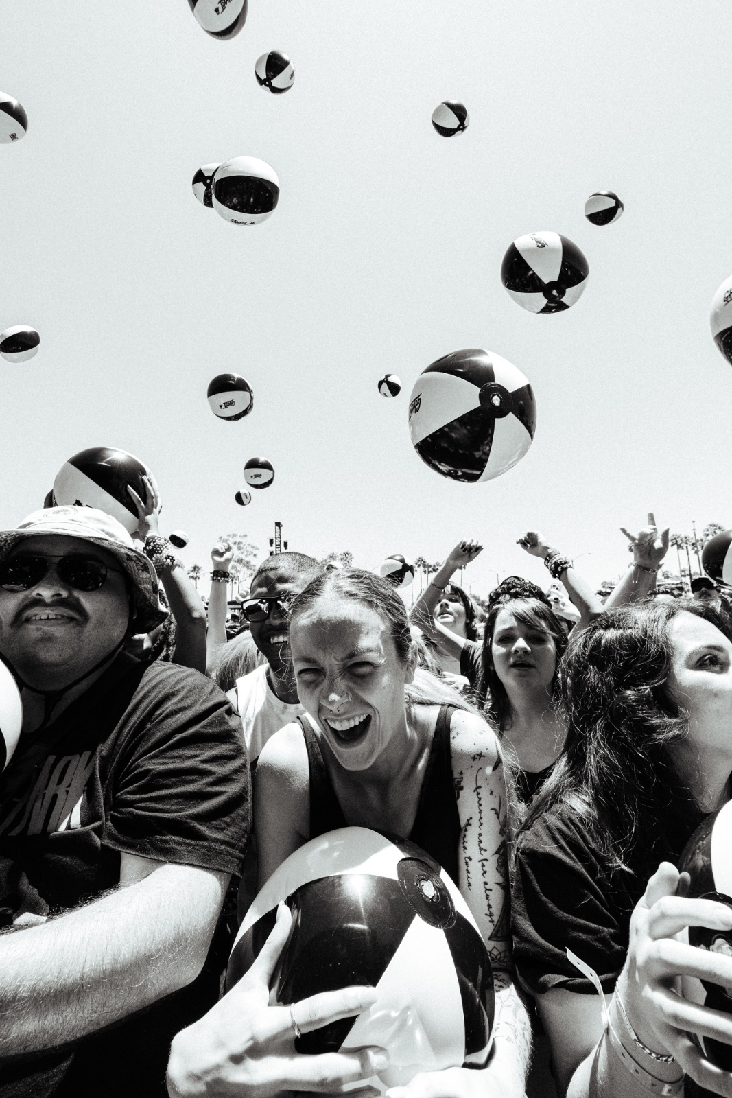 Black-and-white crowd shot with branded beach balls flying overhead